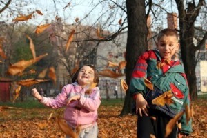 little-boy-and-girl-playing-with-autumn-leaves-in-the-park
